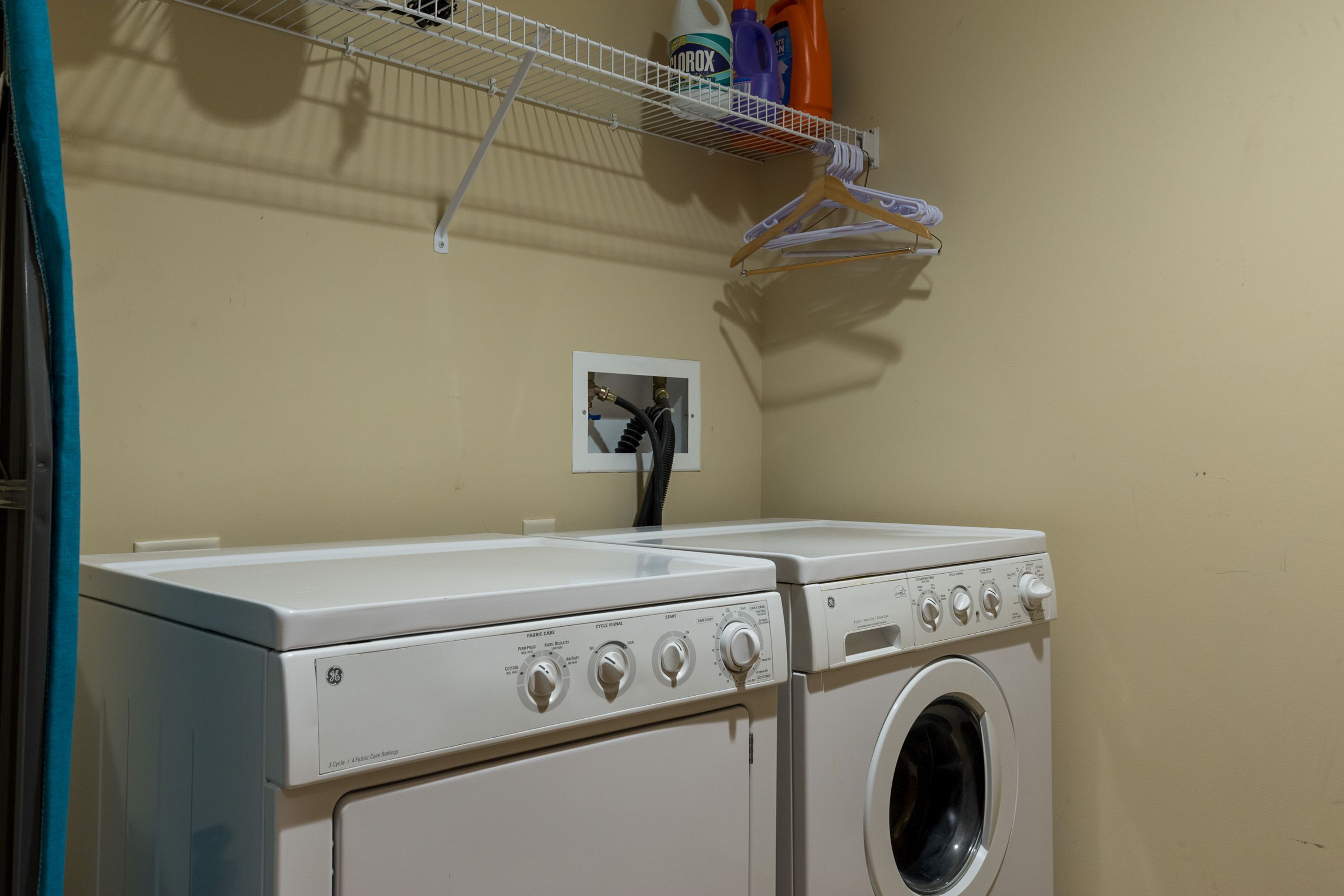 A laundry area with two washing machines and a drying rack.