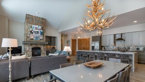 A modern living room with a fireplace, a dining area, and a kitchen with granite countertops. - Lone Eagle by Summit County Mountain Retreats (Keystone)
