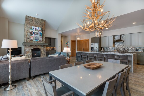 A modern living room with a fireplace, a dining area, and a kitchen with granite countertops.