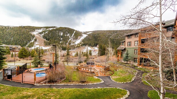 Un complexe hôtelier doté d’une piscine, d’une terrasse en bois et offrant une vue sur les montagnes.
