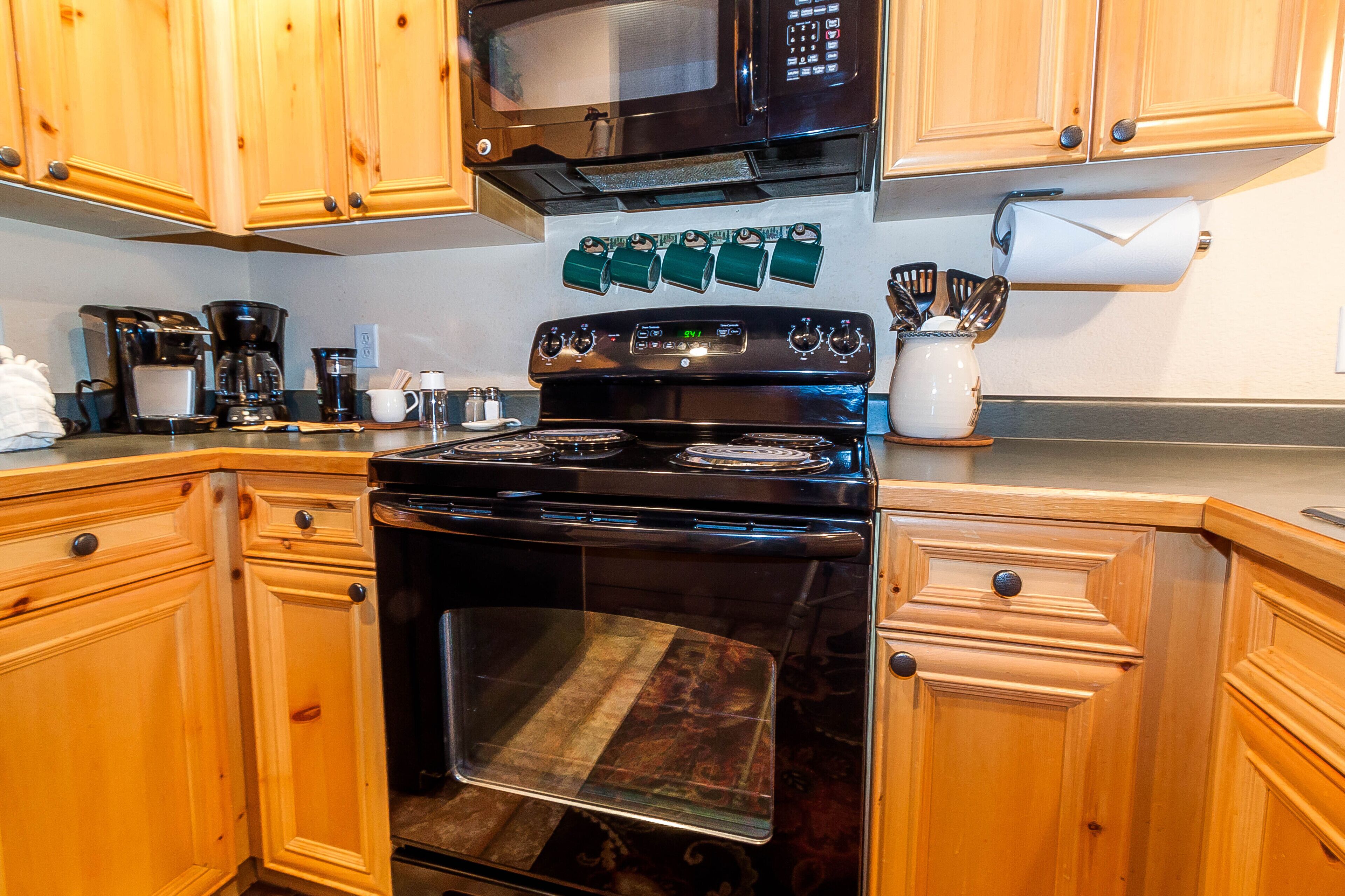 Una cucina con mobili in legno, un piano cottura nero, un forno a microonde e una macchina da caffè.