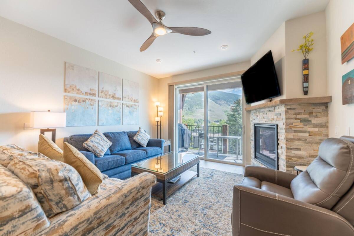 A living room with a sofa, armchair, and coffee table, a fireplace, and a TV mounted on the wall.