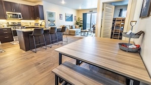 Una cocina moderna con armarios de madera oscura, un microondas de acero inoxidable y una isla central con taburetes de bar.