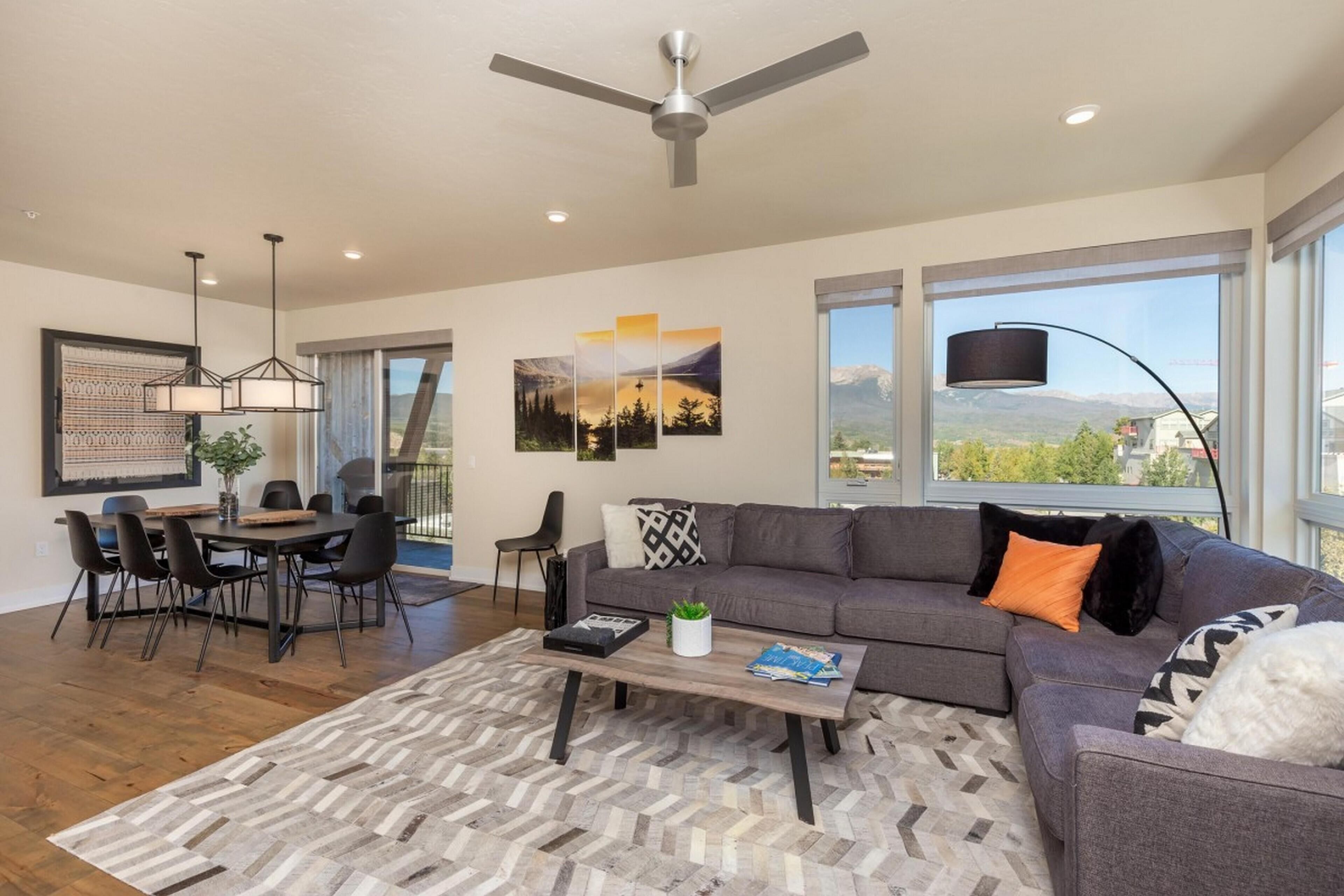 A modern living room with a gray sofa, a coffee table, and a dining area with a table and chairs.