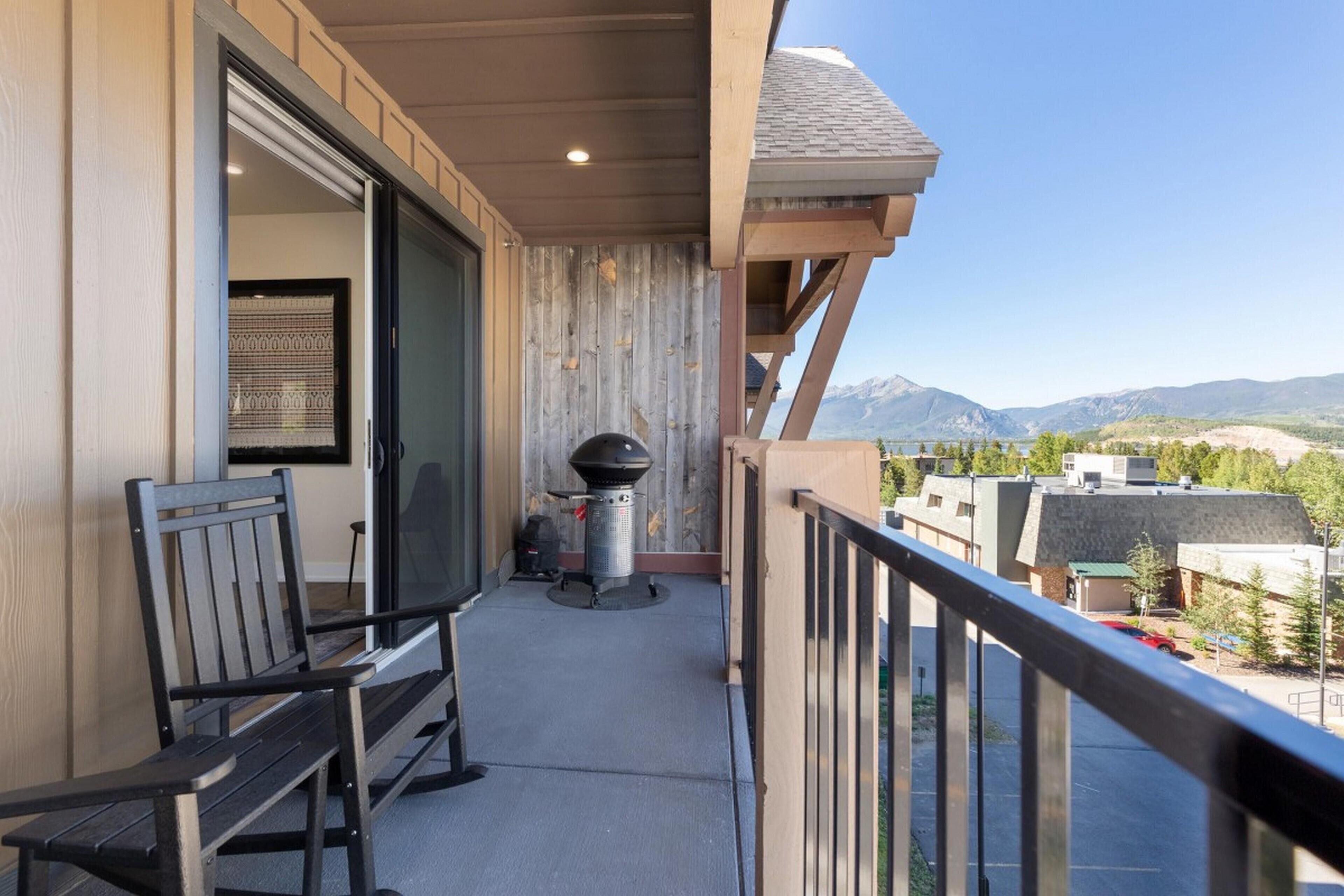 A balcony with a grill, a bench, and a view of mountains.