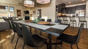 Un comedor moderno con una mesa larga, sillas negras e iluminación colgante.