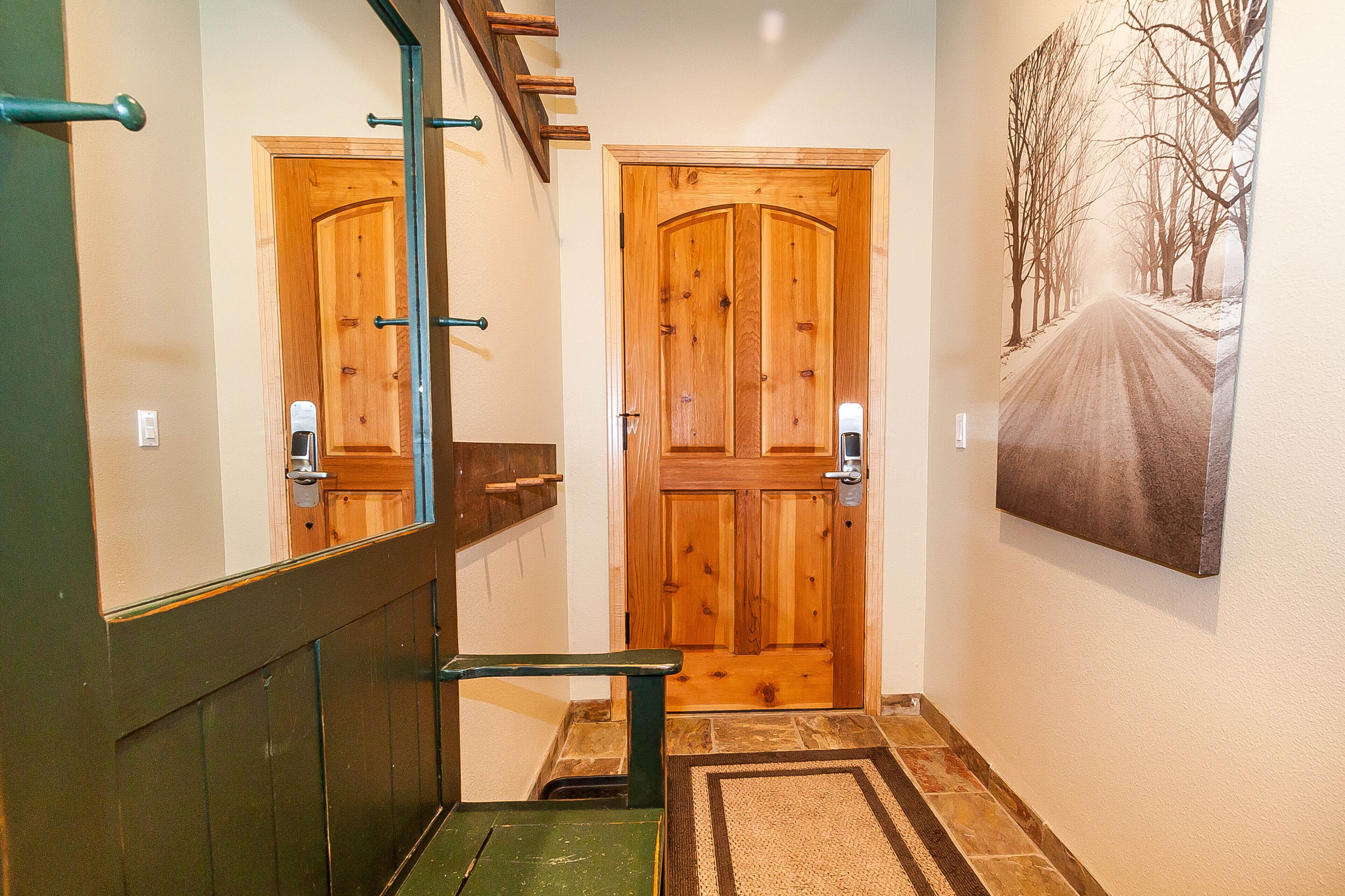 A hallway with wooden doors, a mirror, and a painting of a road.