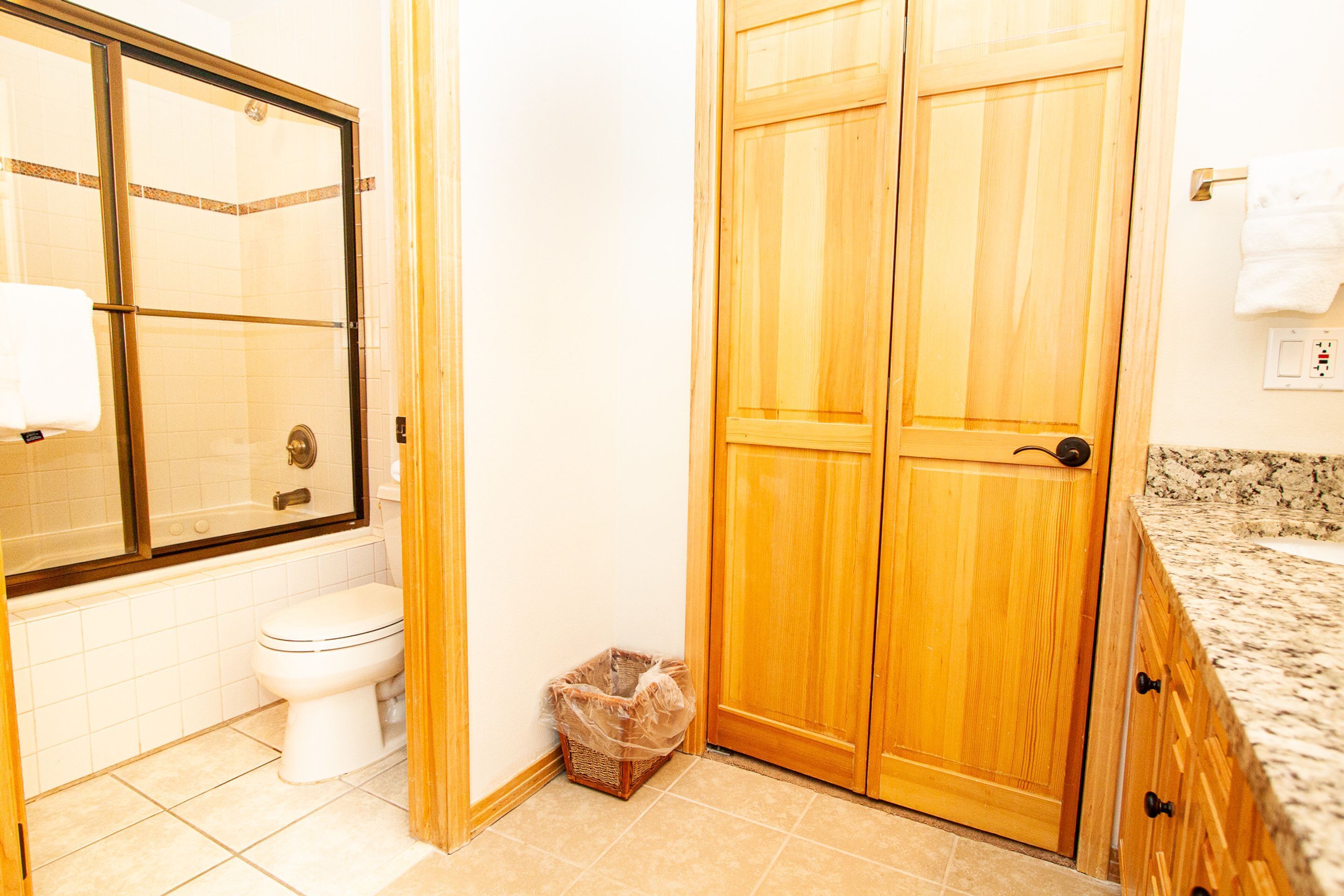 A bathroom with a toilet, shower, and wooden double doors.
