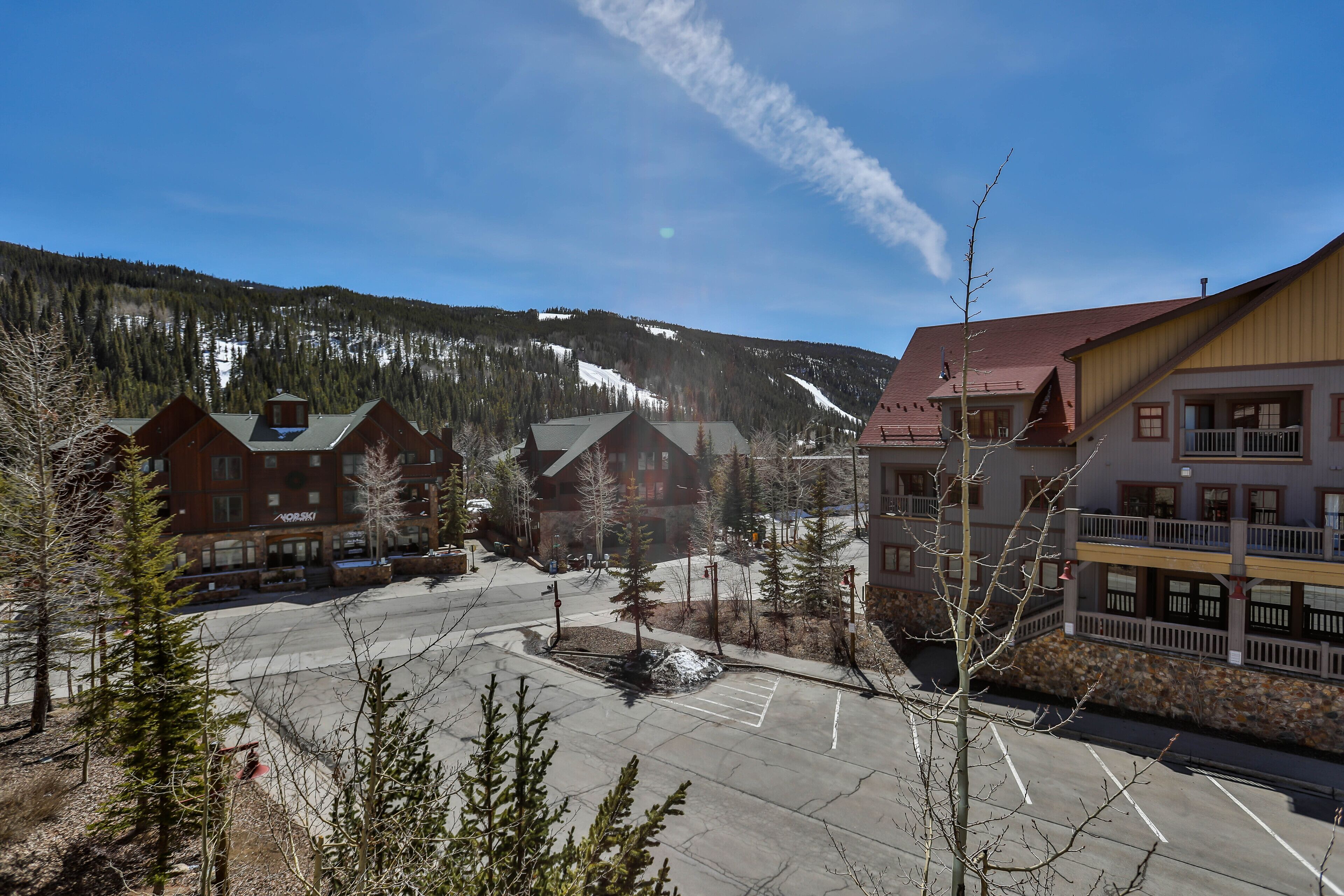 A hotel with multiple buildings, a parking lot, and a mountainous backdrop.
