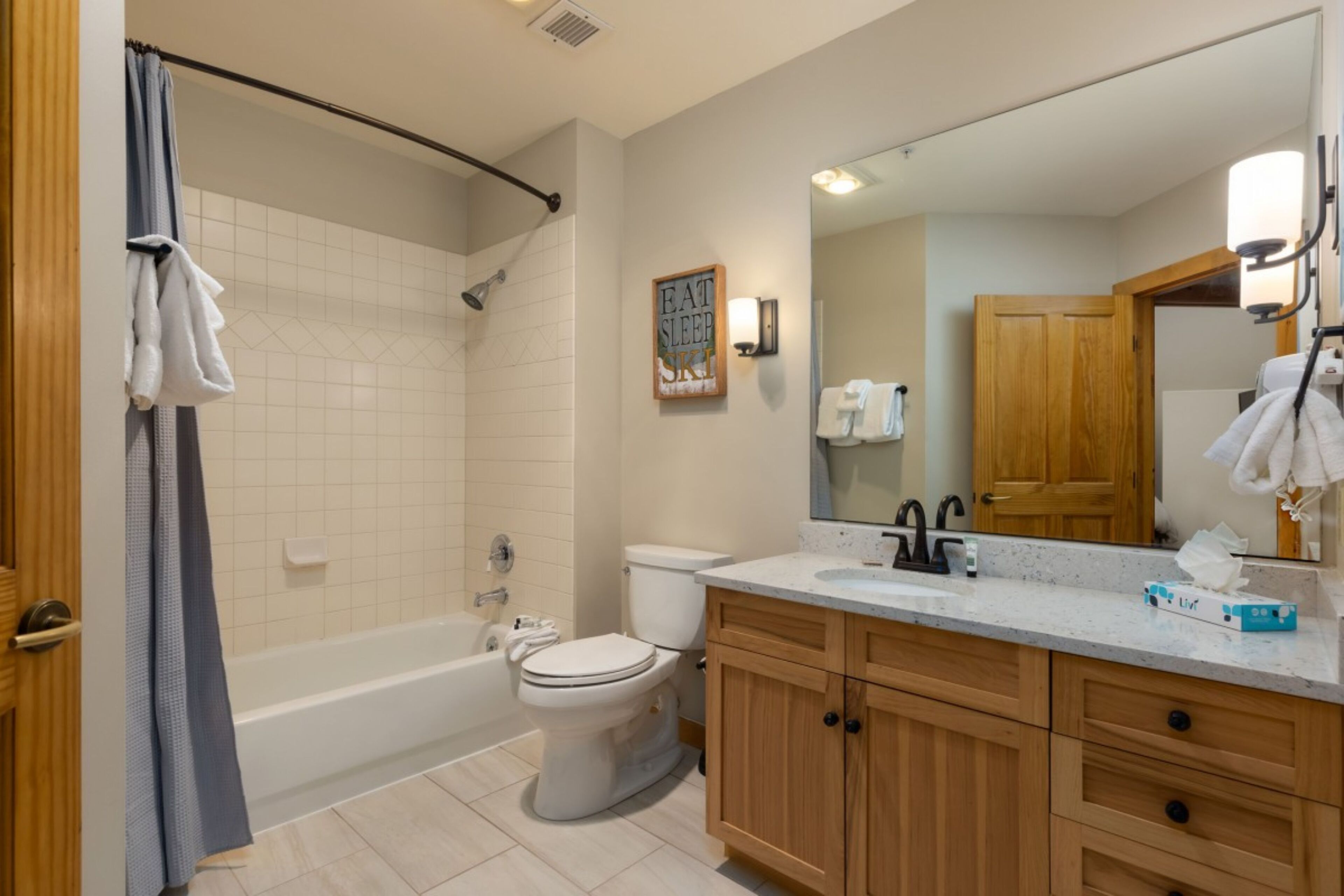 A bathroom with a bathtub, toilet, and vanity with a mirror.