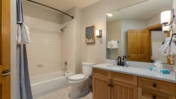 A bathroom with a bathtub, toilet, and vanity with a mirror.