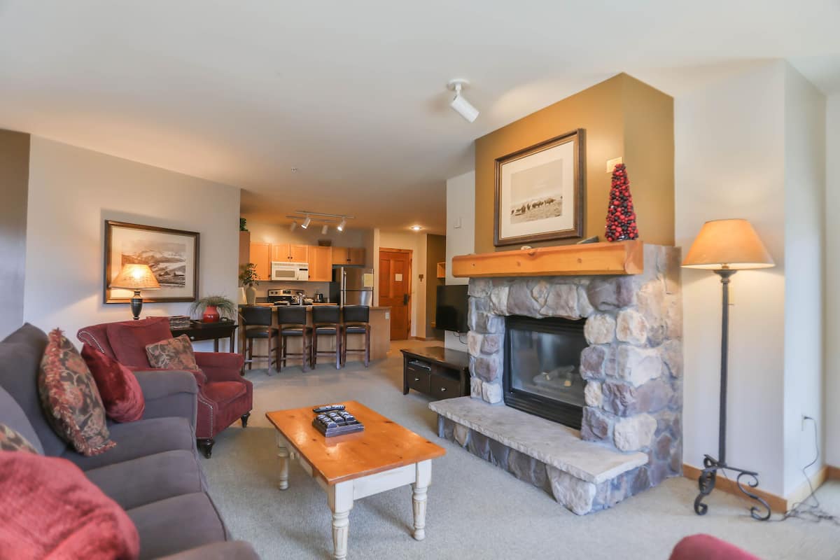 A living room with a fireplace, a sofa, a coffee table, and a television.