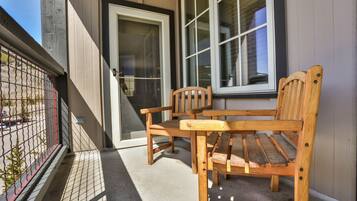A wooden bench and table outside a building with a glass door and windows.