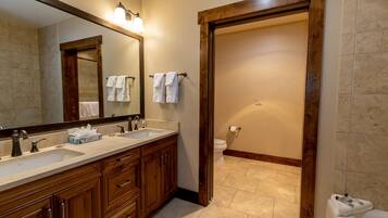 Une salle de bain avec deux lavabos, un grand miroir, des meubles en bois et des toilettes.