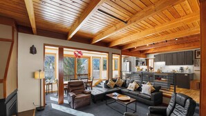A spacious living area with a large sofa, leather chairs, and a coffee table. A kitchen is visible in the background with modern appliances. - Tennis Townhome #1337 by Summit County Mountain Retreats (Keystone)