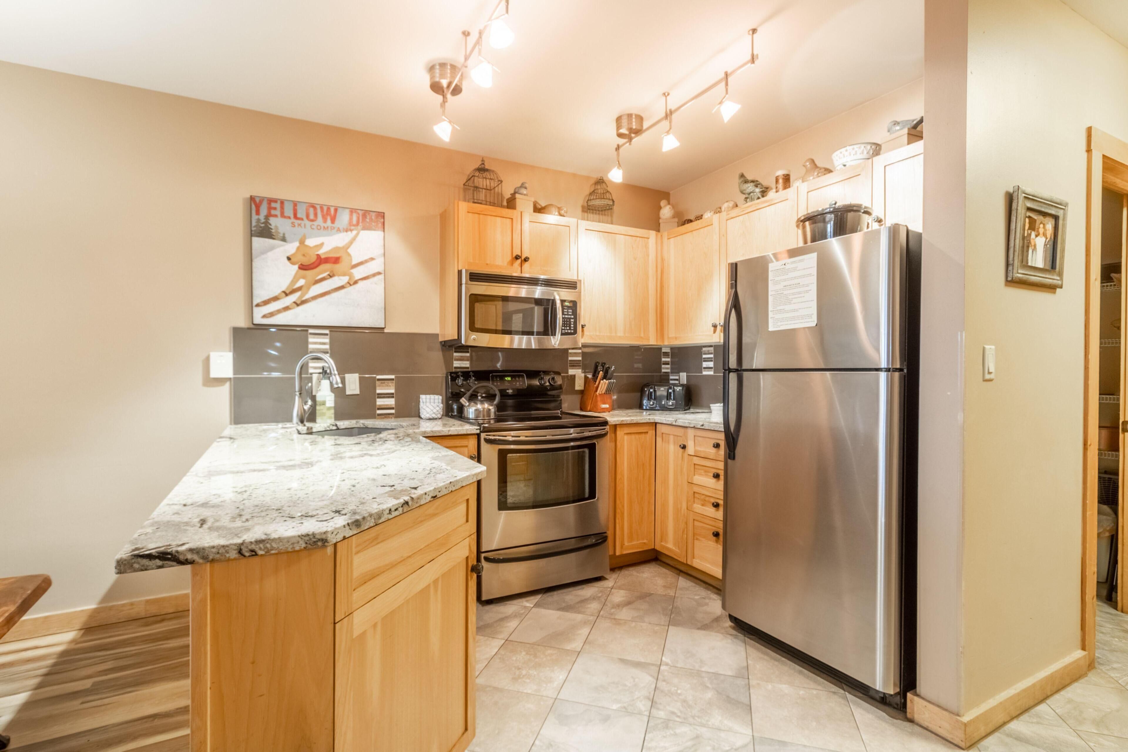 A modern kitchen with wooden cabinets, stainless steel appliances, and a granite countertop.