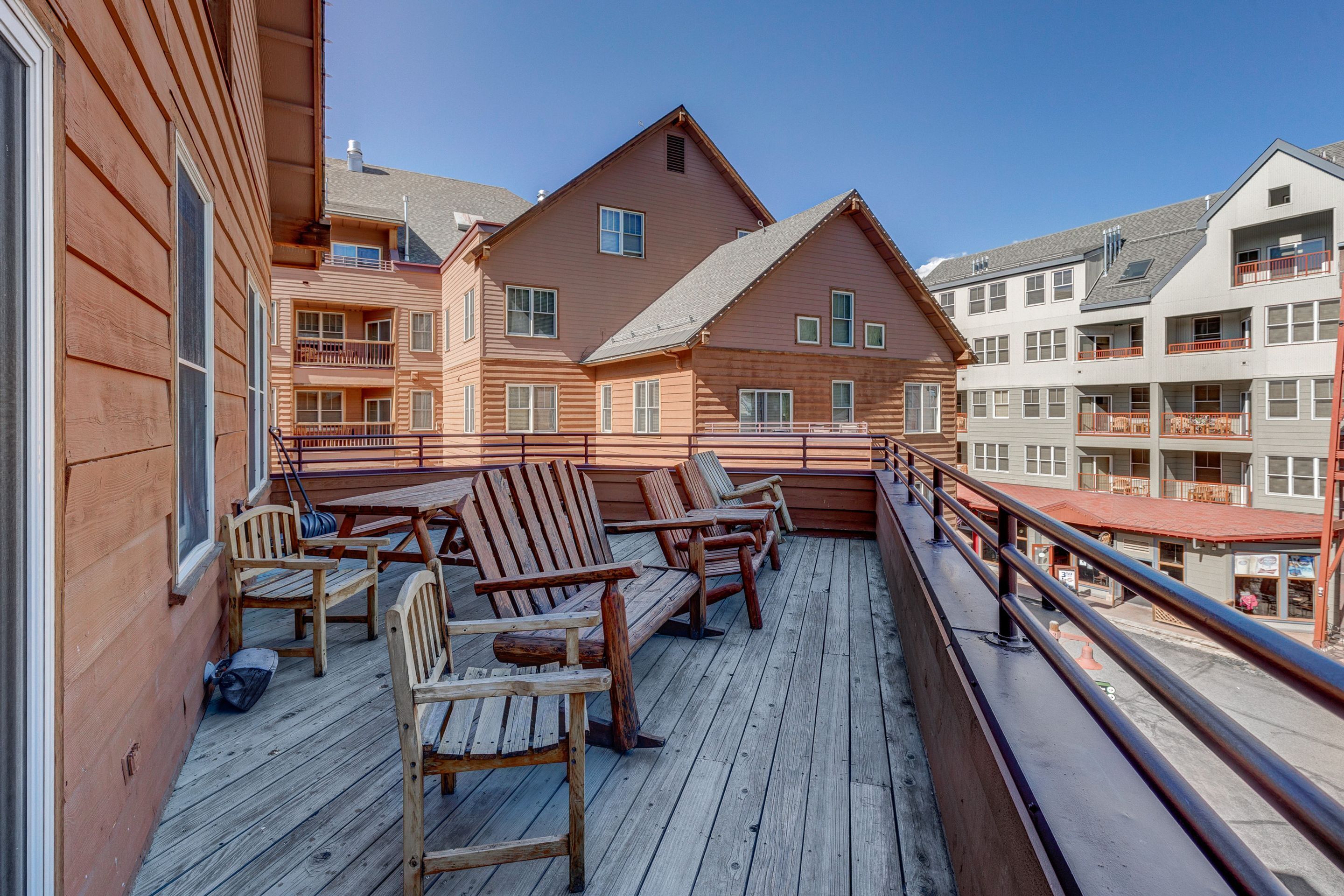 A wooden deck with outdoor seating and a view of multi-story buildings.