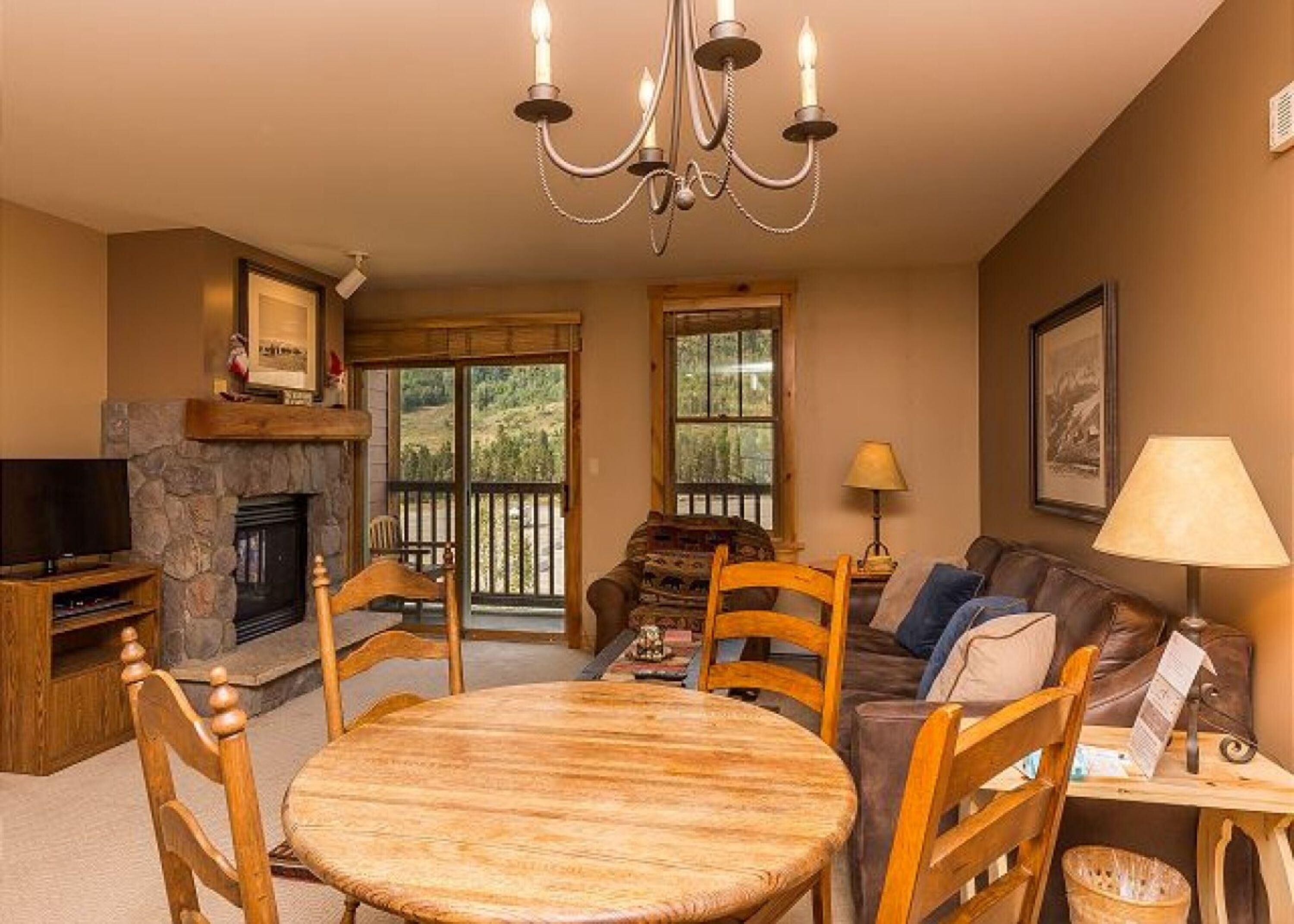 A cozy living room with a stone fireplace, a wooden dining table, and comfortable seating.