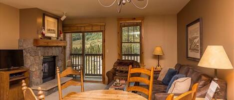 A cozy living room with a stone fireplace, a wooden dining table, and comfortable seating.