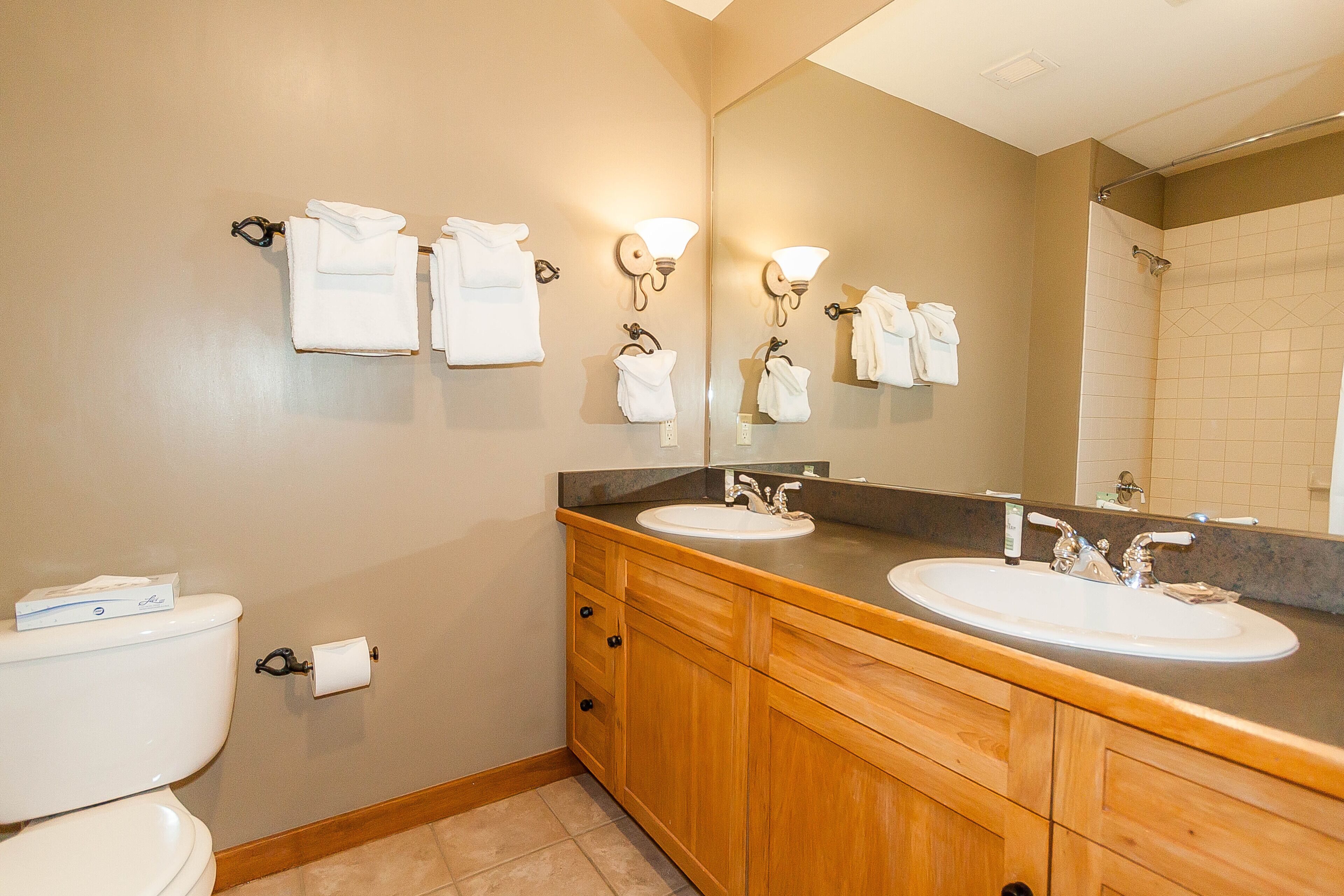 A bathroom with two sinks, a toilet, and a large mirror.