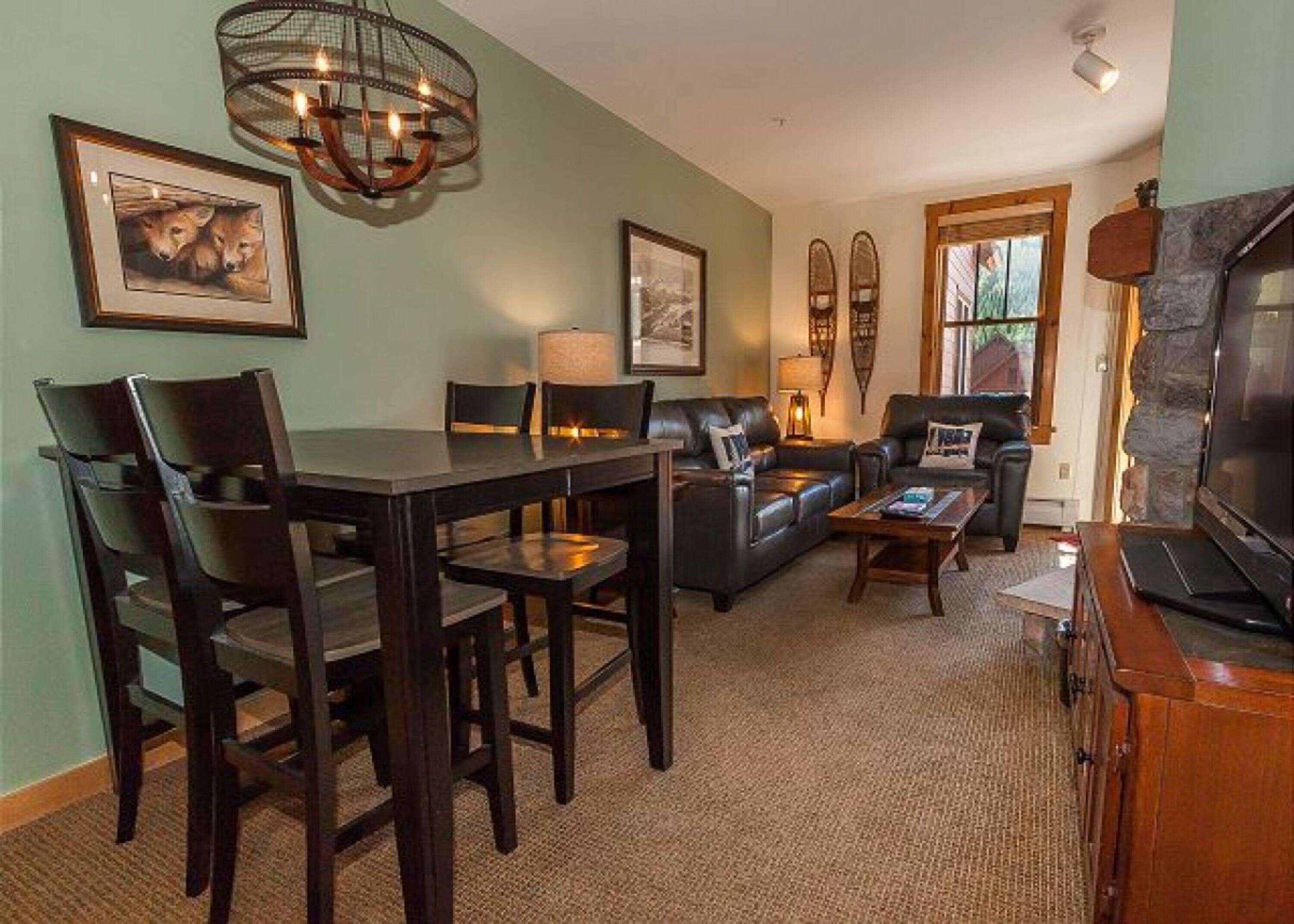 A living room with a dining table, chairs, a sofa, and a television.