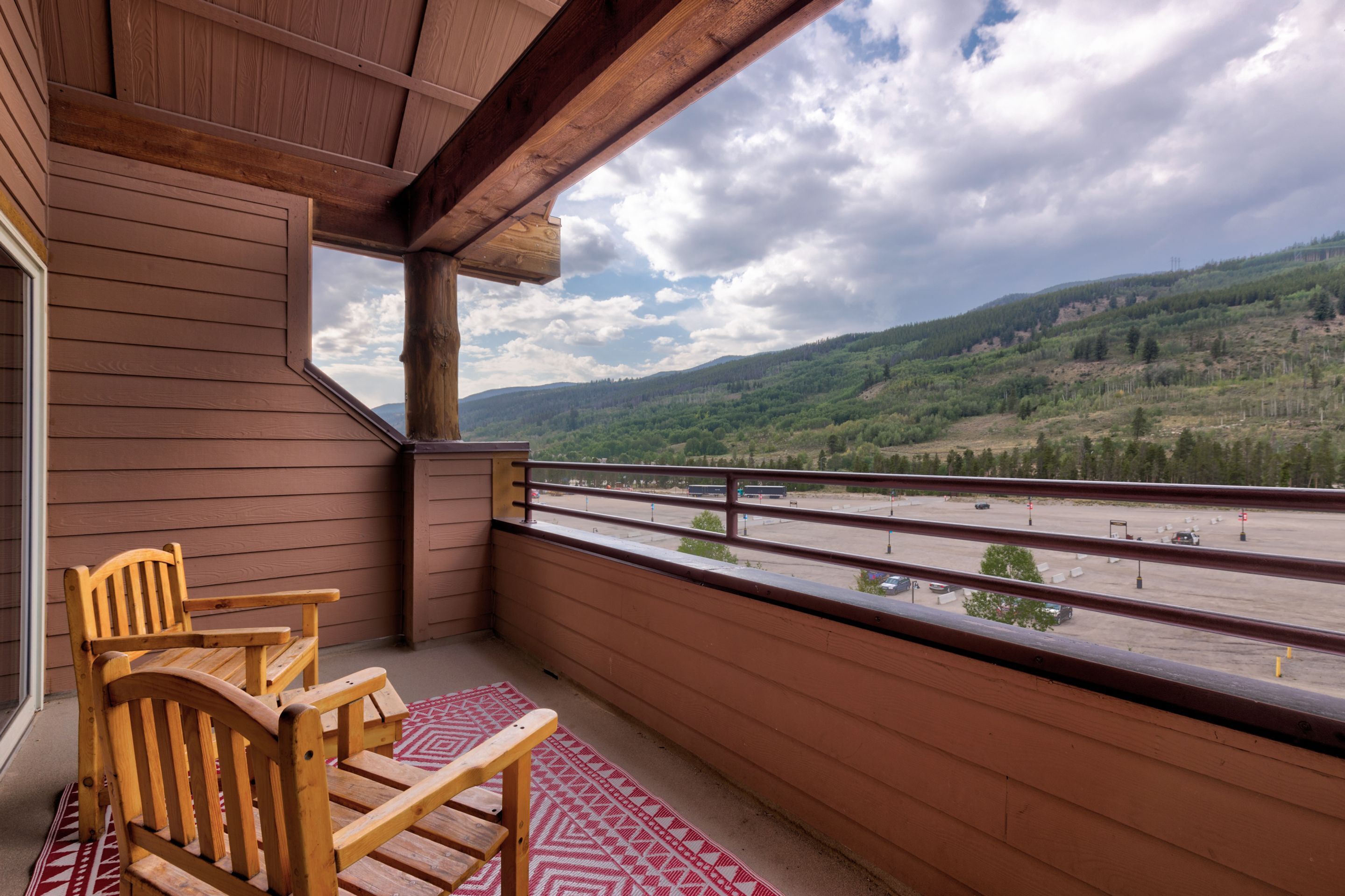 A wooden deck with two chairs and a view of a highway and hills.
