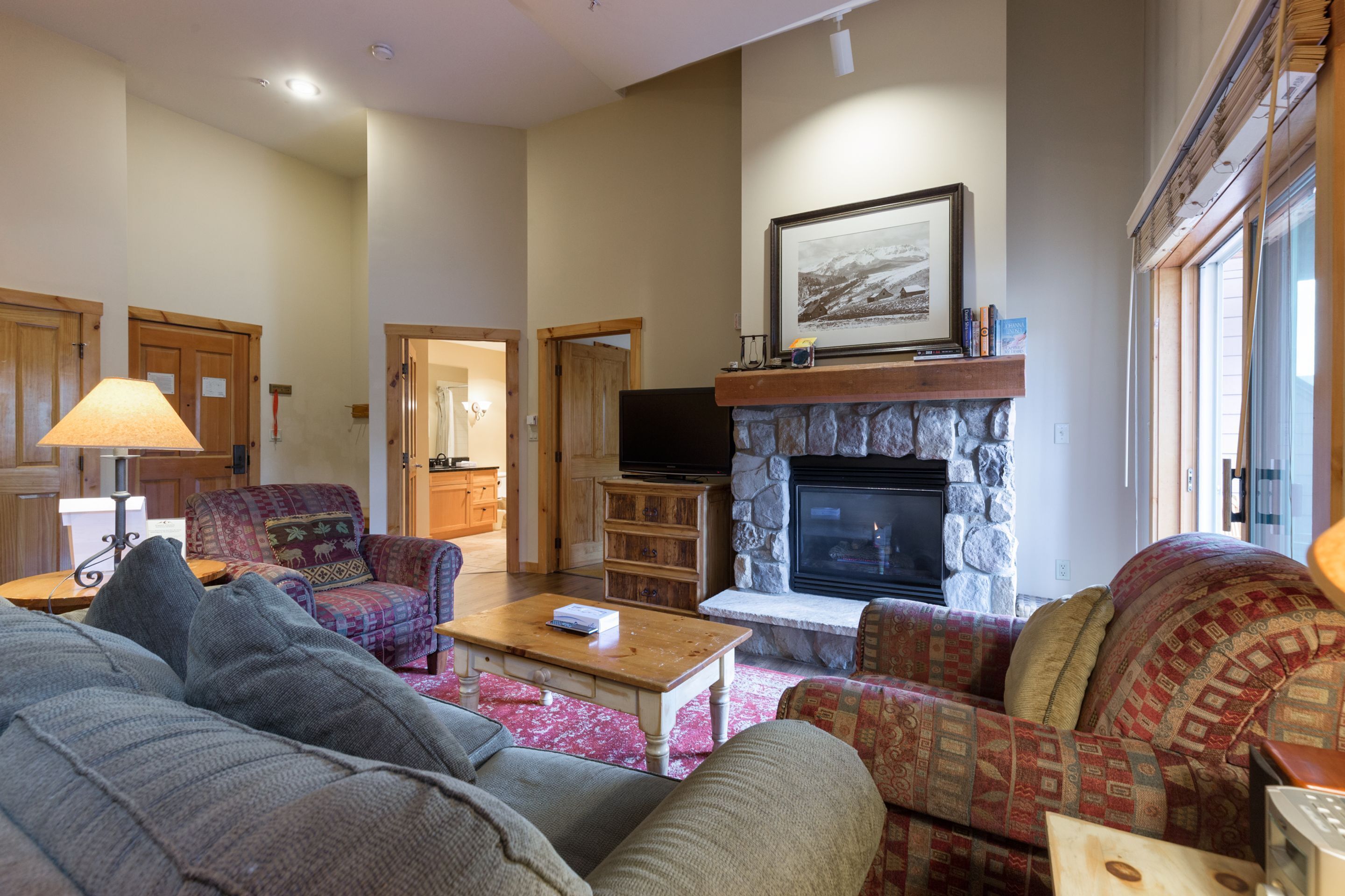 A cozy living room with a stone fireplace, comfortable seating, and a television.