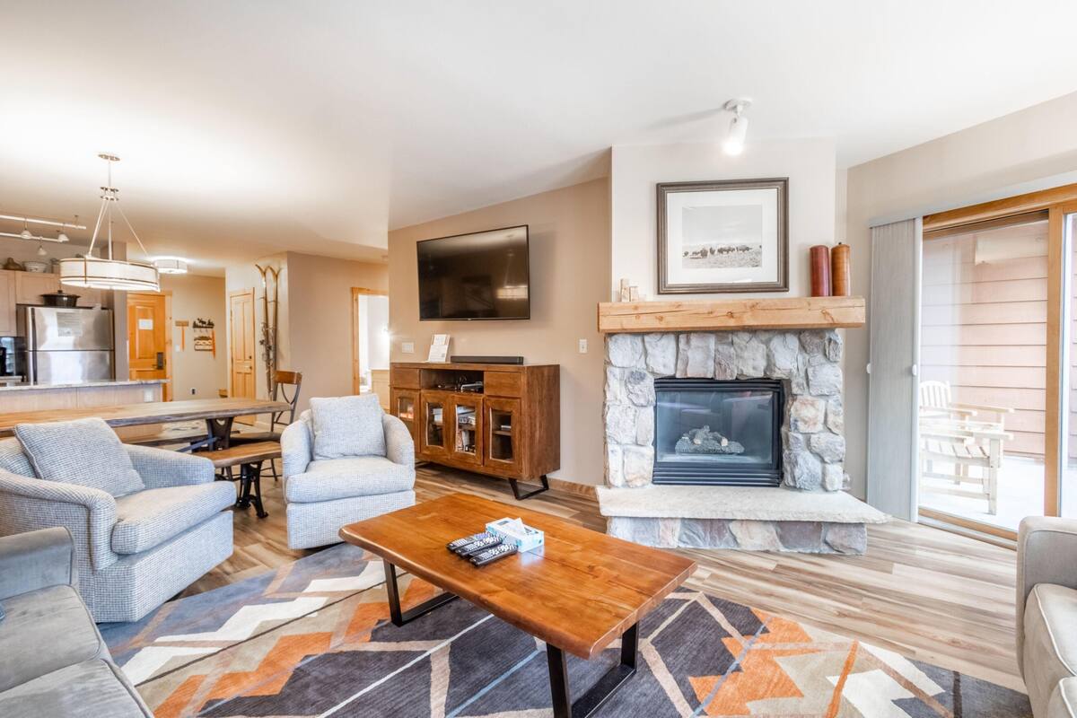 A modern living room with a fireplace, comfortable seating, and a dining area.