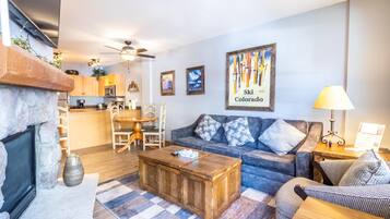 A living room with a fireplace, a sofa, a coffee table, and a dining area with chairs and a table.