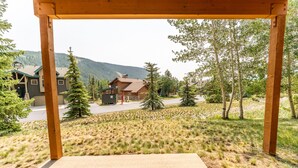Une pergola en bois surplombant un quartier résidentiel avec des maisons et une chaîne de montagnes en arrière-plan.