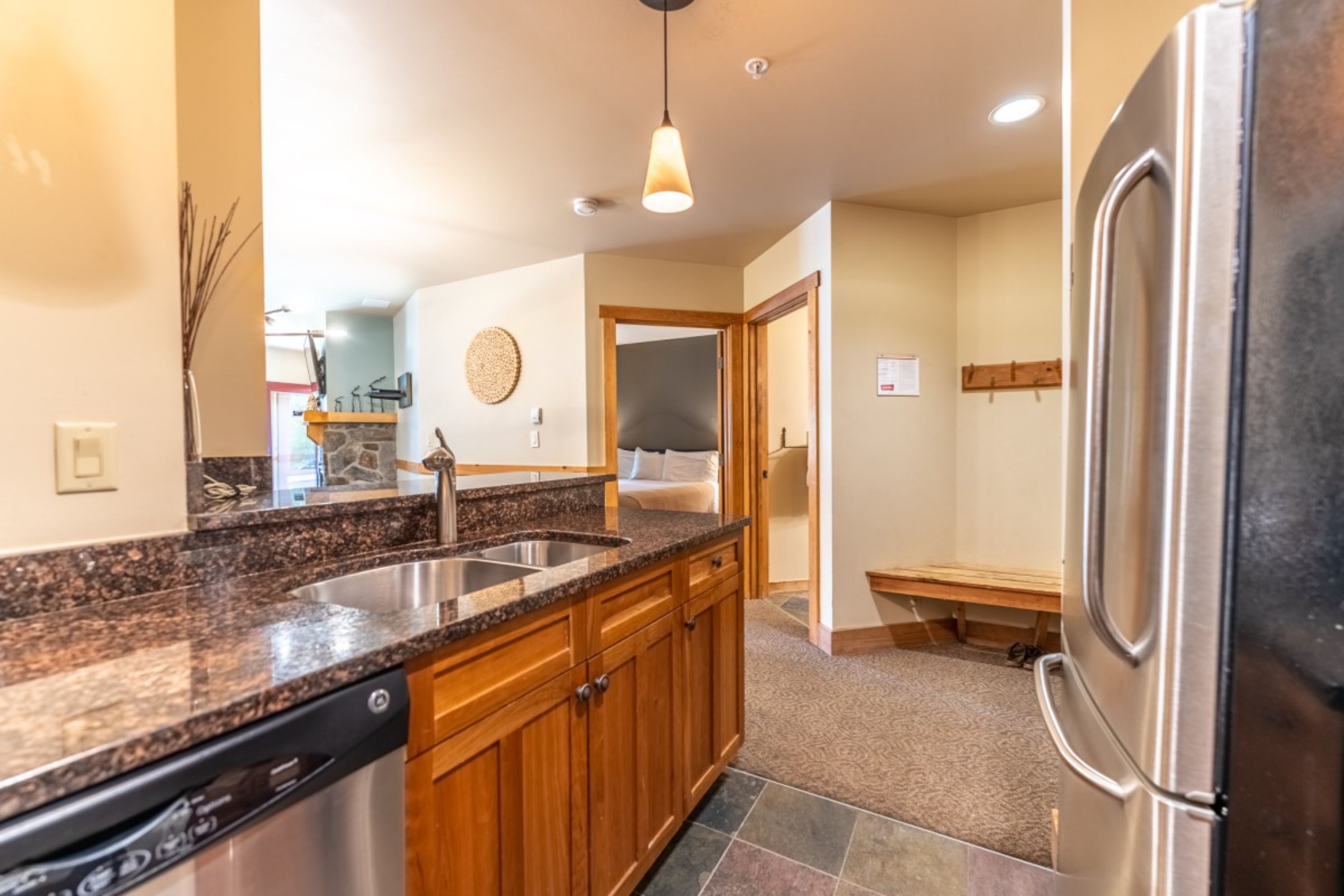 A kitchen with granite countertops, wooden cabinets, a stainless steel refrigerator, and a built-in dishwasher.