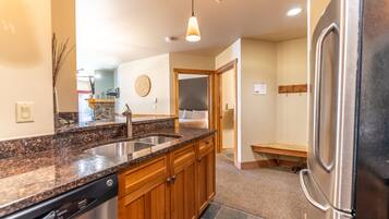 A kitchen with granite countertops, wooden cabinets, a stainless steel refrigerator, and a built-in dishwasher.