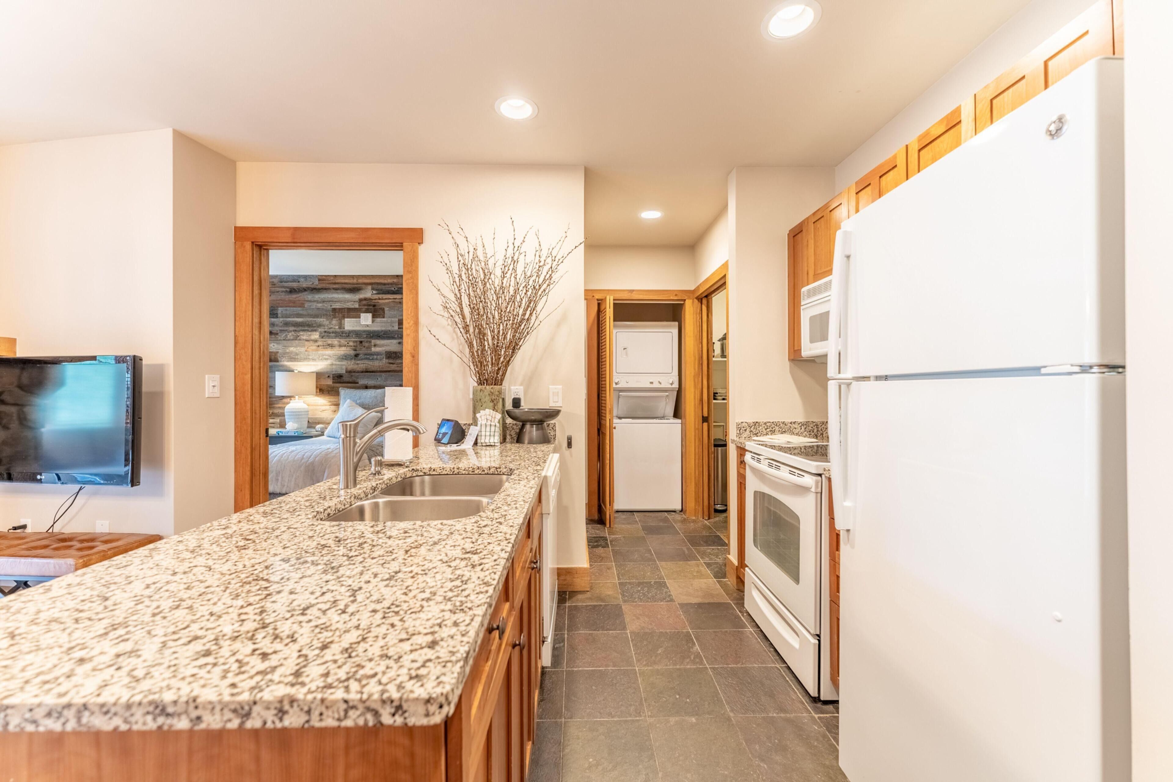 A modern kitchen with granite countertops, stainless steel appliances, and wooden cabinets.