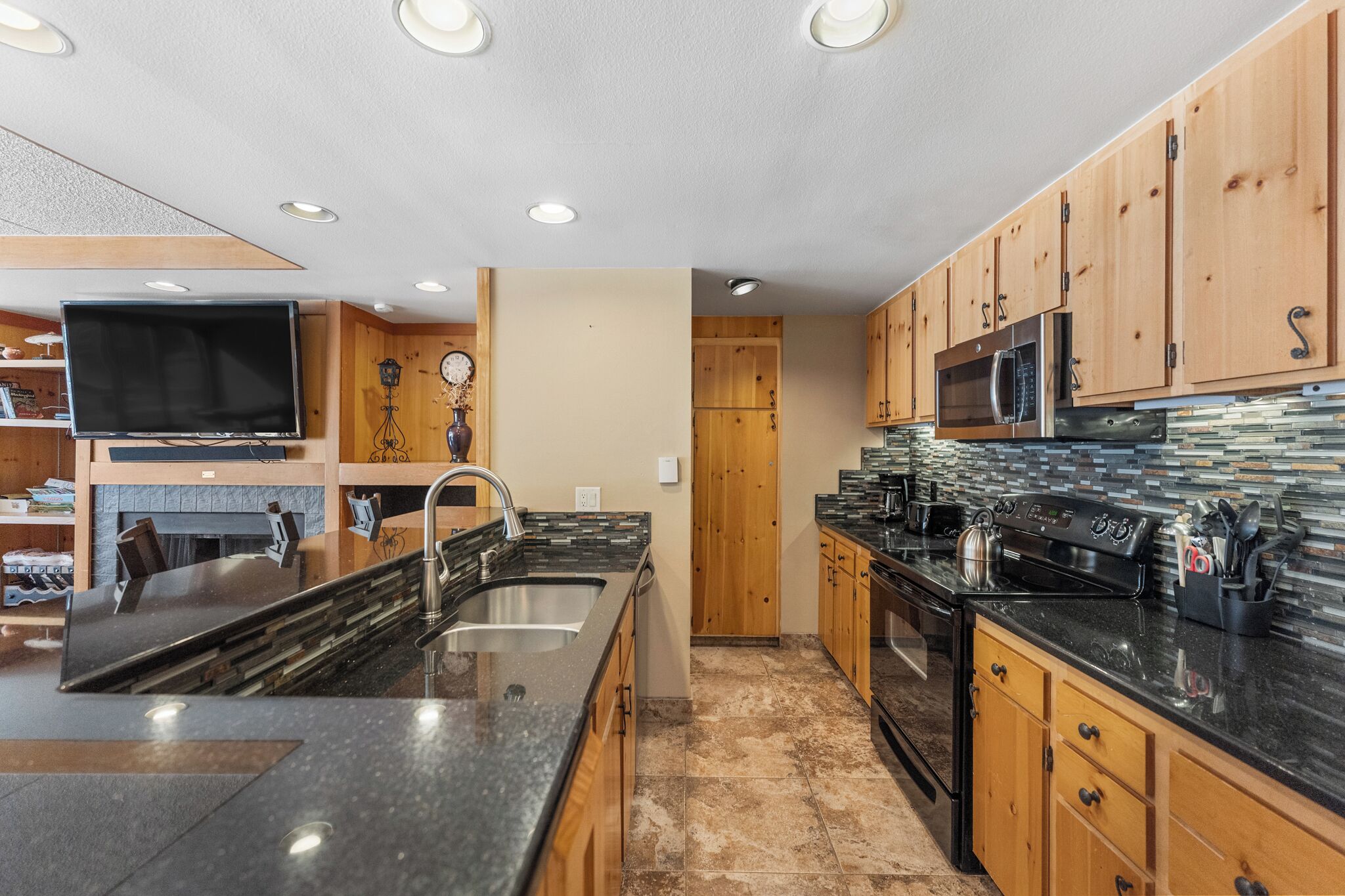 A modern kitchen with wooden cabinets, a large island with a sink, and stainless steel appliances.