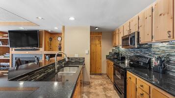A modern kitchen with wooden cabinets, a large island with a sink, and stainless steel appliances.
