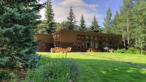Un chalet doté d’une grande terrasse, entouré d’un jardin bien entretenu et d’arbres imposants.