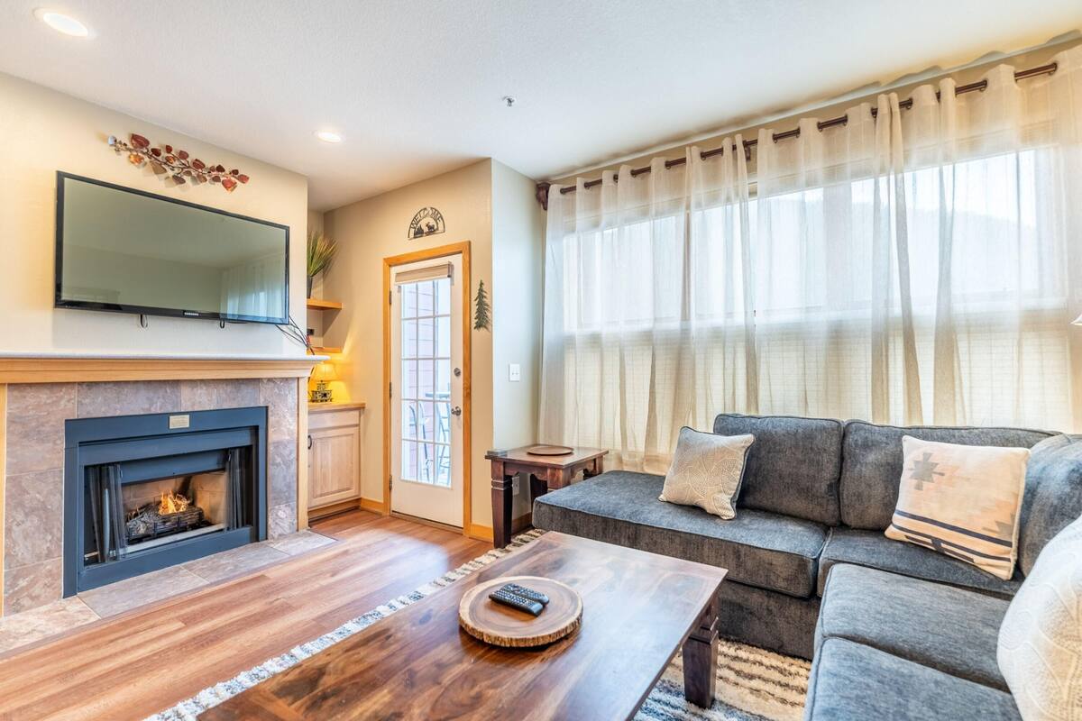A living room with a fireplace, a sofa, and a television mounted on the wall.
