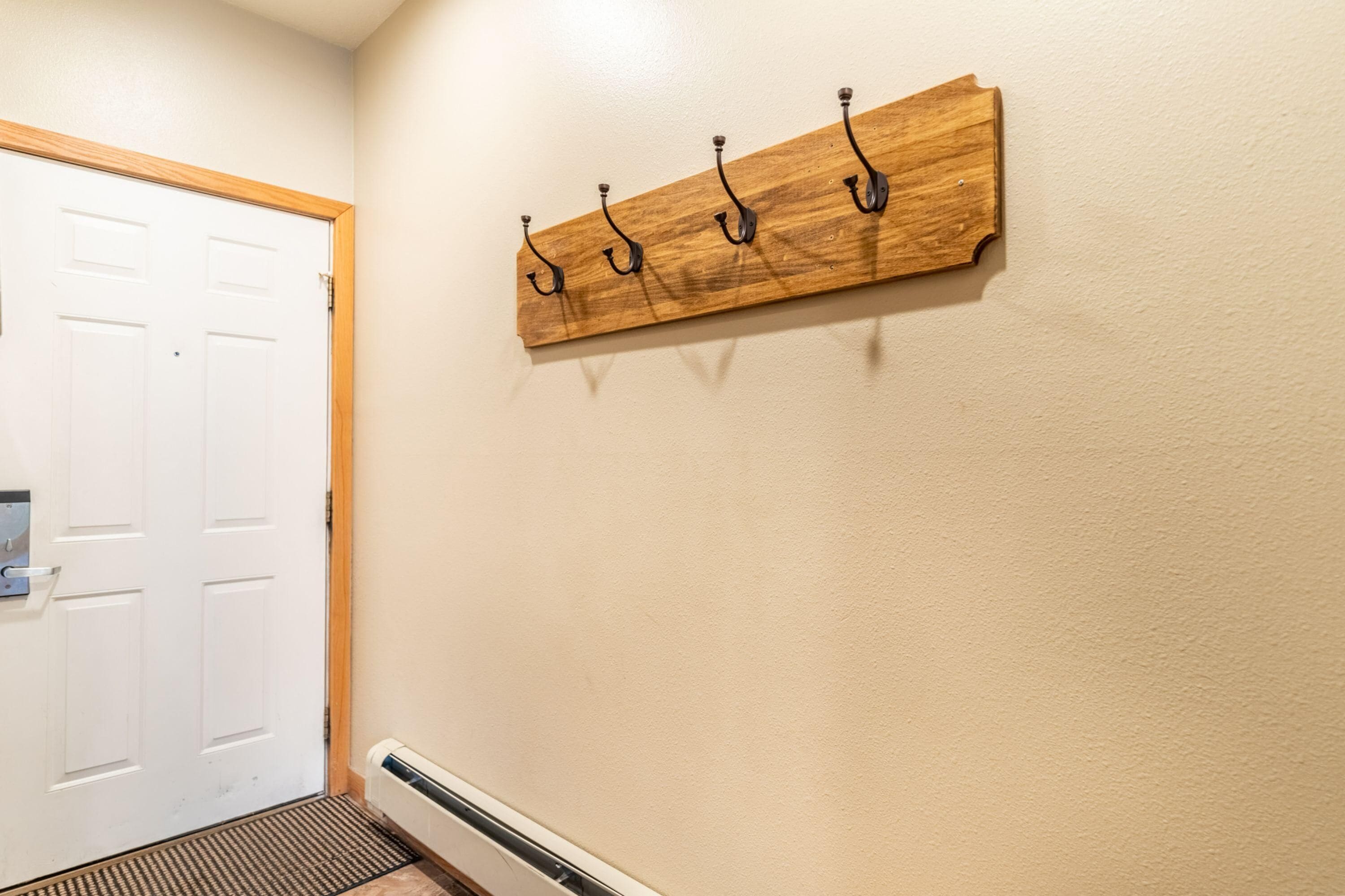 A hallway with a wooden wall-mounted coat rack and a white door.