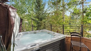 A hot tub on a balcony with a view of trees and a chair. - Rasor Court #20 by Summit County Mountain Retreats (Keystone)