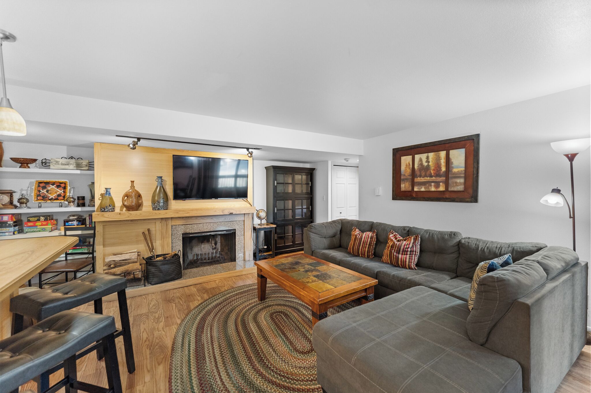 A living room with a fireplace, a sofa, a coffee table, and a dining area with a wooden table and benches.