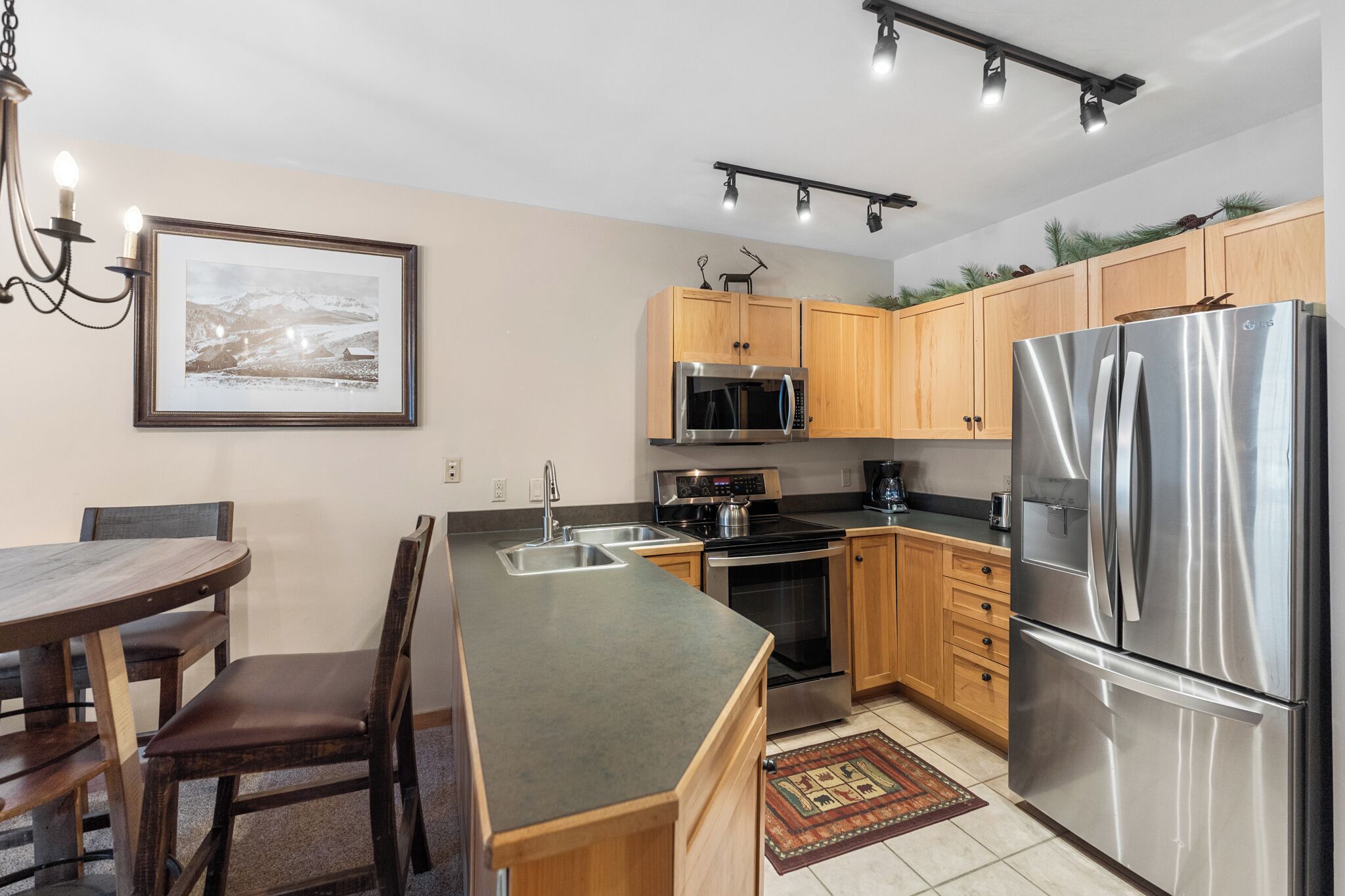 A modern kitchen with wooden cabinets, stainless steel appliances, and a dining area with a table and chairs.