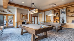 A spacious room with a pool table, a billiards table, and a cozy seating area.
