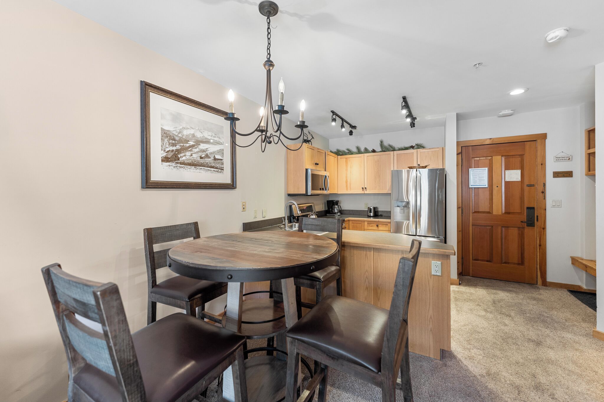 A modern kitchen with wooden cabinets, a central island, and a chandelier.