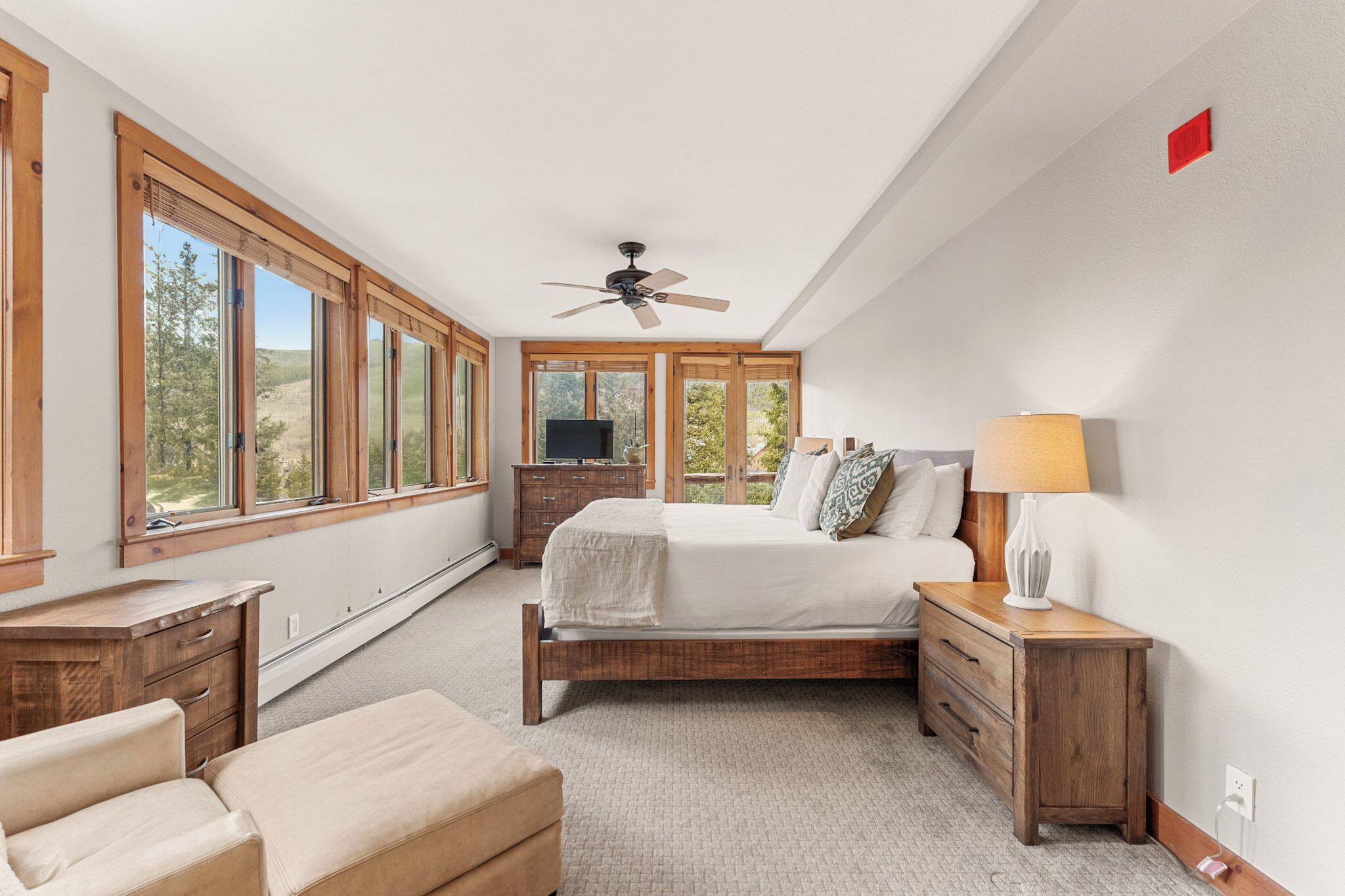 A bedroom with a bed, wooden nightstands, a dresser, and a TV.
