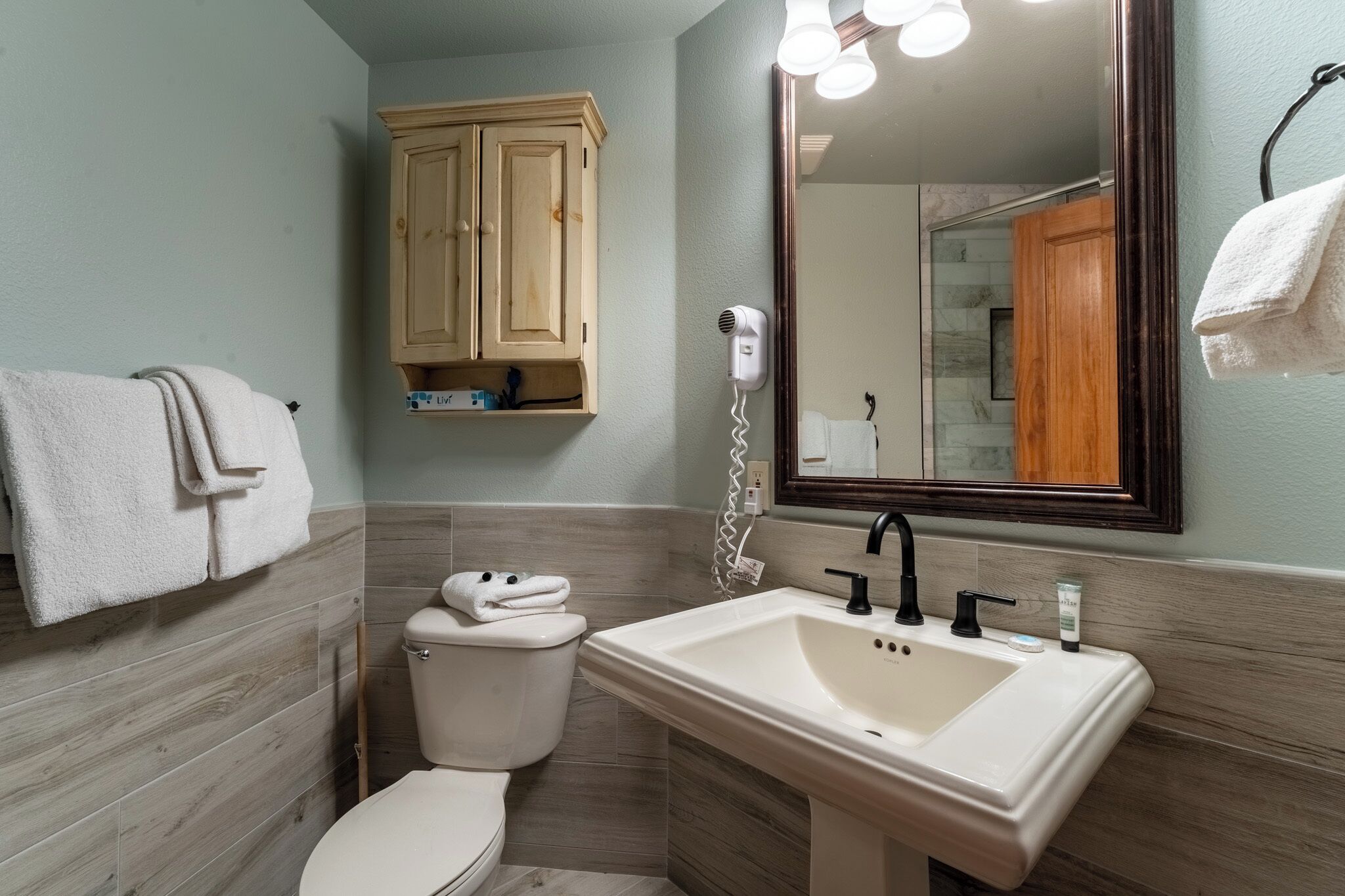 A bathroom with a toilet, a sink, a mirror, and a towel rack.