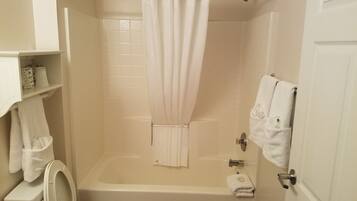 A bathroom with a bathtub, toilet, and a shower curtain.