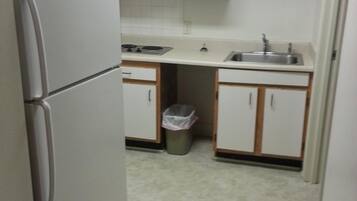 Una cocina compacta equipada con refrigerador, microondas, pileta y basurero.