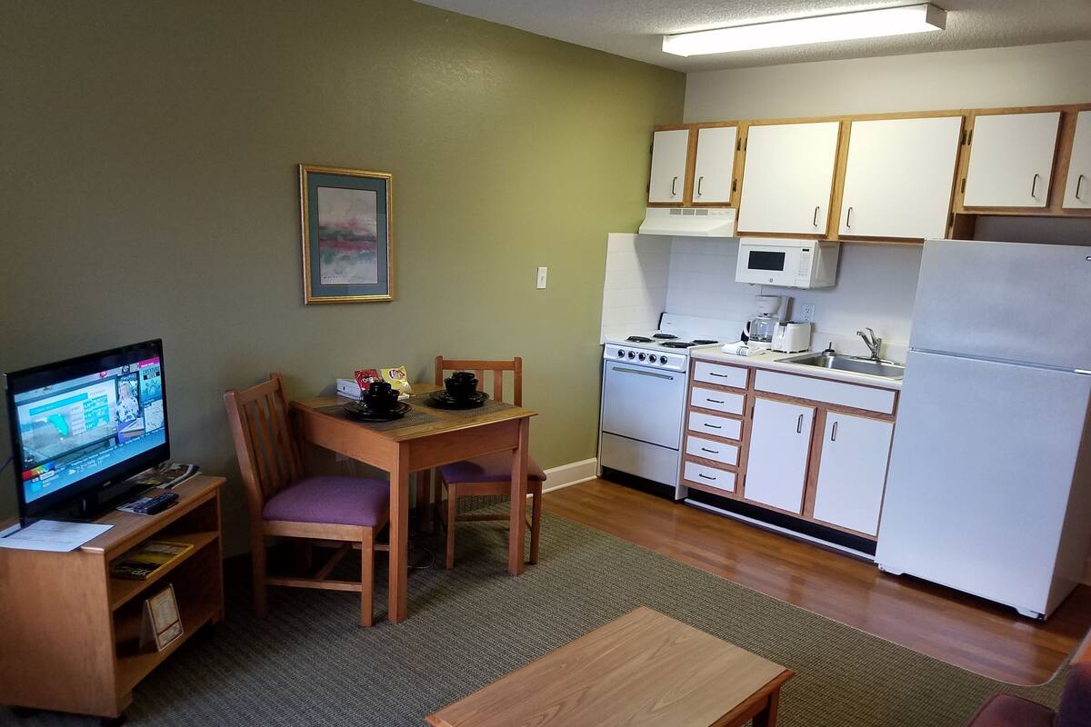 A compact kitchen with a dining area, a TV, and a small table.