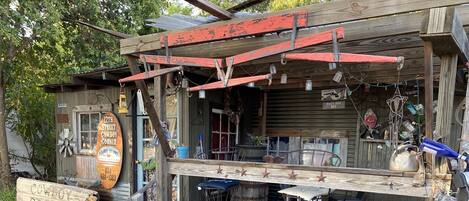 A rustic wooden building with a porch, a sign reading "Cowboy Corner," and various items displayed outside.