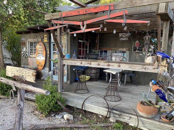 A rustic wooden building with a porch, a sign reading "Cowboy Corner," and various items displayed outside. - 12th St. Cowboy Corner Bandera, TX (Bandera)